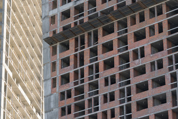 wall with window openings in a multi-storey high-rise residential building under construction from concrete and brick