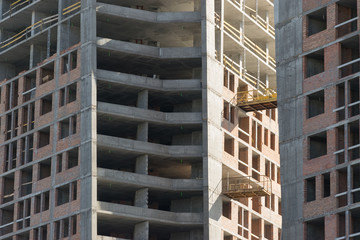 wall with window openings in a multi-storey high-rise residential building under construction from concrete and brick
