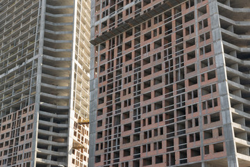 Fototapeta premium wall with window openings in a multi-storey high-rise residential building under construction from concrete and brick