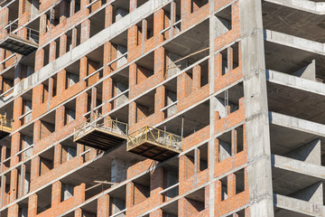 wall with window openings in a multi-storey high-rise residential building under construction from concrete and brick