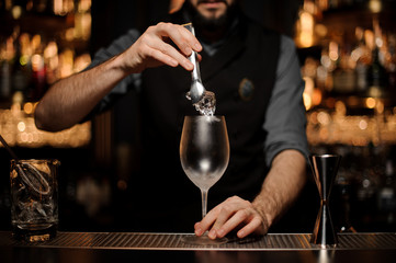 Bartender with a beard puts ice in glass