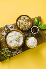 Fototapeta na wymiar Different types of rice on a wooden board made from olive wood. Food background with basil leaves and olive oil. healthy home cooking
