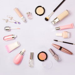 Square image of cosmetics for social media with empty place for text. Woman make up cosmetics on purple. Copy space. Gold and purple decorative cosmetic: highlighter, concealer, rouge, eye shadows etc