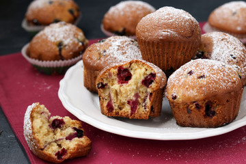Fototapeta na wymiar Black currant muffins in a plate on a pink background