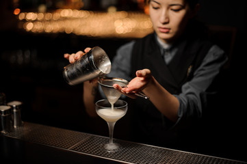 Bartender pours an alcohol cocktail in glass