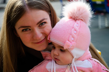 Mom plays on a bright playground with a small child in the street, nomads, a house during the day