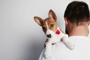 Handsome bearded man snuggling and hugging his basenji puppy dog, close friendship against a white background. Copy paste space mock-up