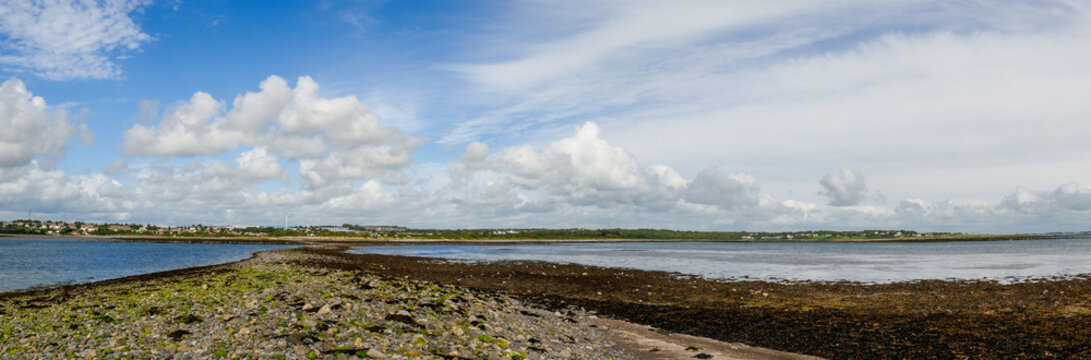 Panorama image, path from Hare island, Galway, Ireland. Sunny day, Very low tide. blue sky and the Atlantic ocean.