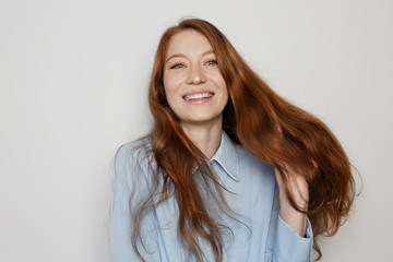 Obraz premium Youth and happiness female.Beautiful Caucasian teenage woman with long ginger hair and freckles, dressed casually, standing against blank white wall.Copy paste space, studio shot, model.