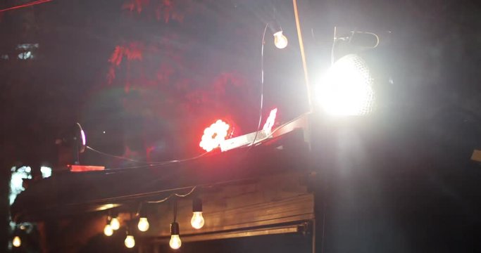 View of the shining disco ball reflecting light rotating on the roof of the club at summer night.