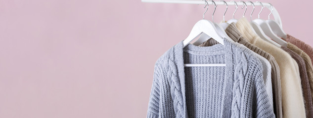 Warm knitted clothes hanging on a rack