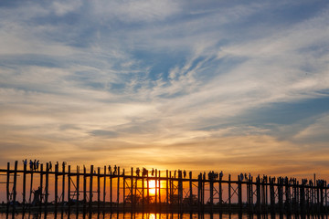 Obraz premium Sunset over U Bein Wooden bridge with locals' and tourists' silhouettes, Mandalay, Myanmar