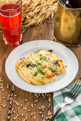 Baked fish with cheese sauce and berry drink on wooden table