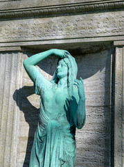 Frauenstatue vor einem Grabstein 