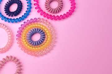 Plastic spiral scrunchies for women hairdressing hairstyle on pink background with free copy space for text