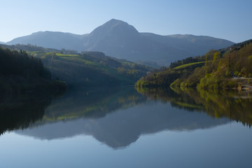 Fototapeta na wymiar mountain in morning light reflected in calm waters of lake, Txindoki, Euskadi