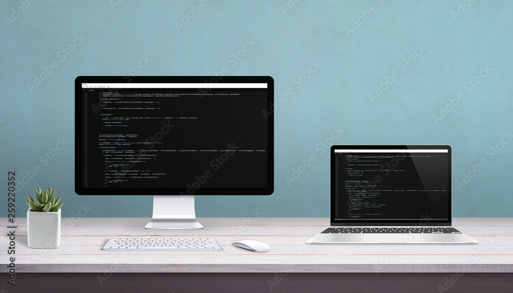 Fototapete Desktop computer and laptop on work desk with programming editor on display. Concept of programming studio.