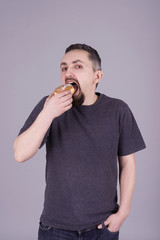 Man with a beard eating a bun over gray background