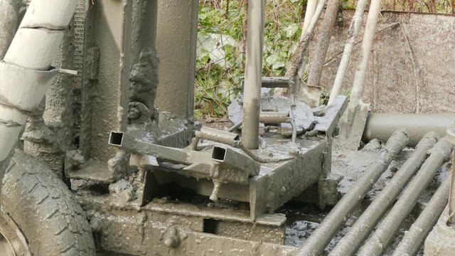 Dirty machine lifts drill up from dirt to create a well