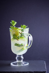 Mojito on a black background. Mojito cocktail with lime and fresh mint on a slate board. Summer refreshing cocktail with citrus on a dark background. Copy space