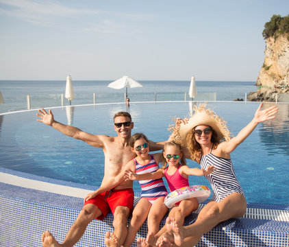 Portrait of happy family with kids near swimming pool on resort