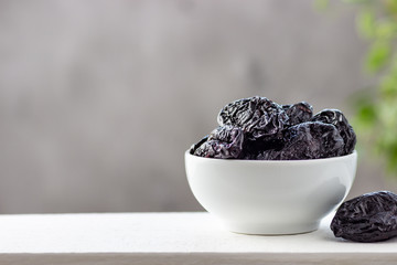 Dried prunes in a white bowl