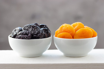 Prunes and dried apricots in white bowls