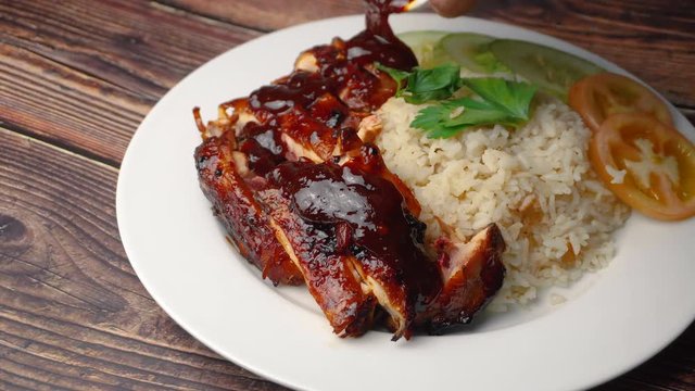pouring sauce on the grilled chicken with rice. 