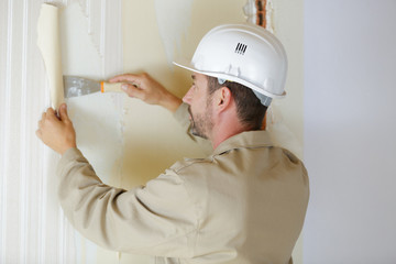 plasterer is removing wallpaper