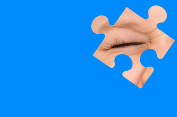 Kid spies through a blue puzzle. Symbol of autism awareness