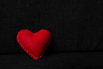 Obraz premium Red valentines day heart made from wool on dark fabric background. Concept of love 