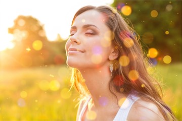 Fototapeta premium Young woman on field under sunset light