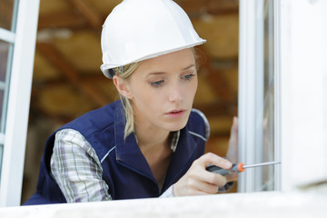 female worker adjusting window with screwdriver