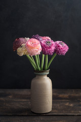 Bouquet of fresh ranunculus flowers in a vase, moody light