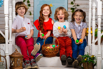 Four cute children, two boys and two girls are sitting next to each other on a wooden threshold...
