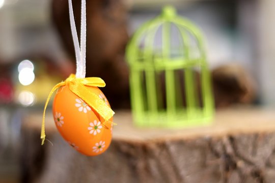 Oeuf de Pâques orange devant une cage miniature