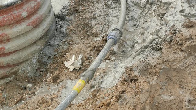Dirty oily fluid seeps from the hole in the hose and runs down the ground