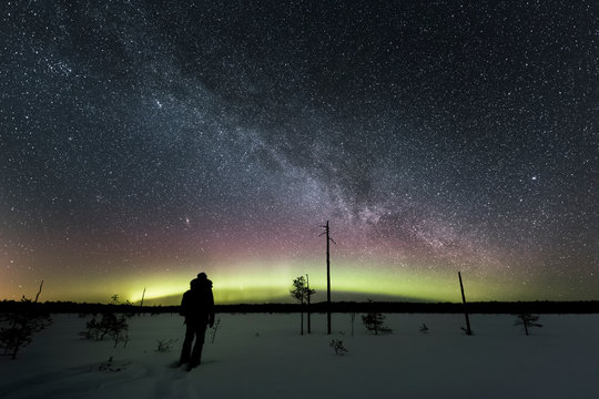 Person watches northern lights over snowy landscape