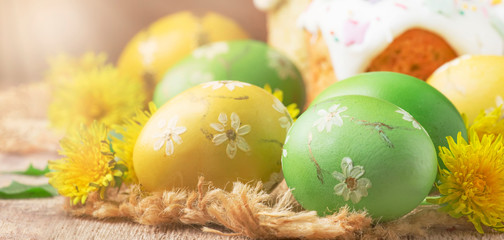 Easter green and yellow painted eggs, yellow dandelion flowers on spring festive composition in rustic style, russian orthodox tradition, vintage wooden background, selective focus