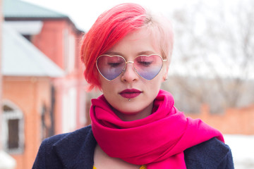 Portrait of an attractive young woman with colored hair and piercing under her lip. Glasses, piercings, multicolored hair