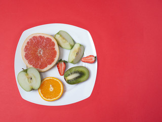 fruit on white plate on red background