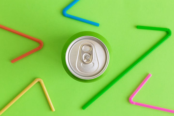 Top view of soda can and multicolored drinking straws abstract on green.