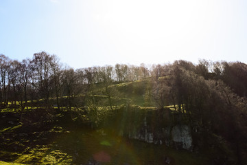 The trees on the hills stand in the sunlight. Springtime. Norway