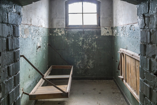 Indoor view of old deserted building, cells of prisoners with doors open in the old prison.