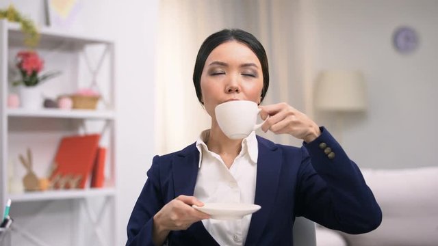 Female office worker enjoying coffee taste imagining home comfort, recreation