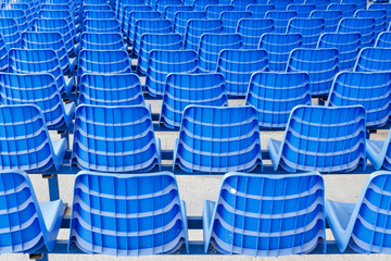 Rows of blue plastic chairs on a metal base. Back view