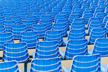 Rows of blue plastic chairs on a metal base. Back view