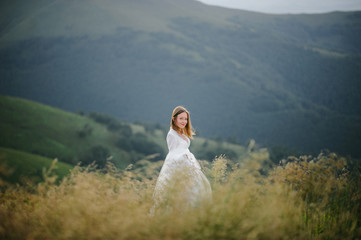 woman in a wedding dress runs across the field toward the mountains