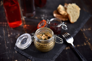 Obraz na płótnie Canvas liver pate with nuts and croutons in a glass jar on a dark background