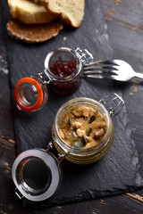 liver pate with nuts and croutons in a glass jar on a dark background